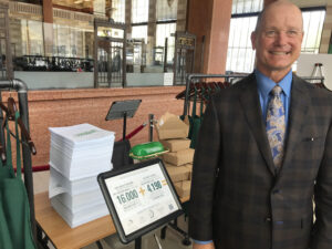 A photo of Dan Walker next to a display of stacks of forms